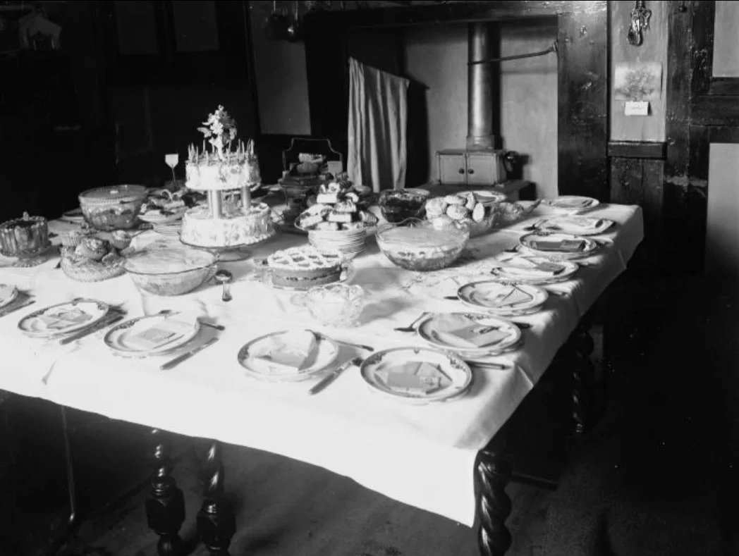 A vintage celebration table laid with cake, bread and dishes