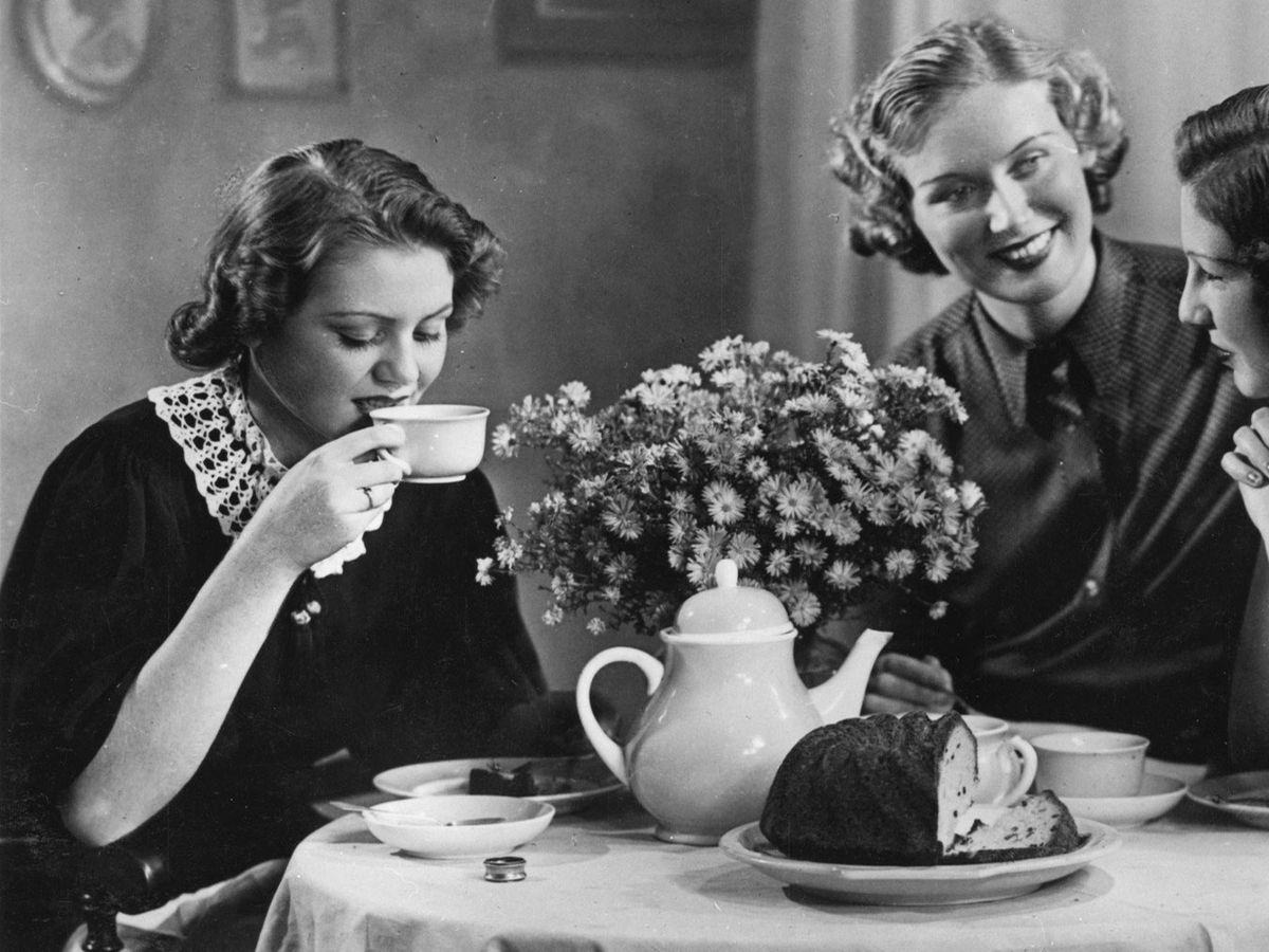 Three friends sharing tea and cake at a vintage table