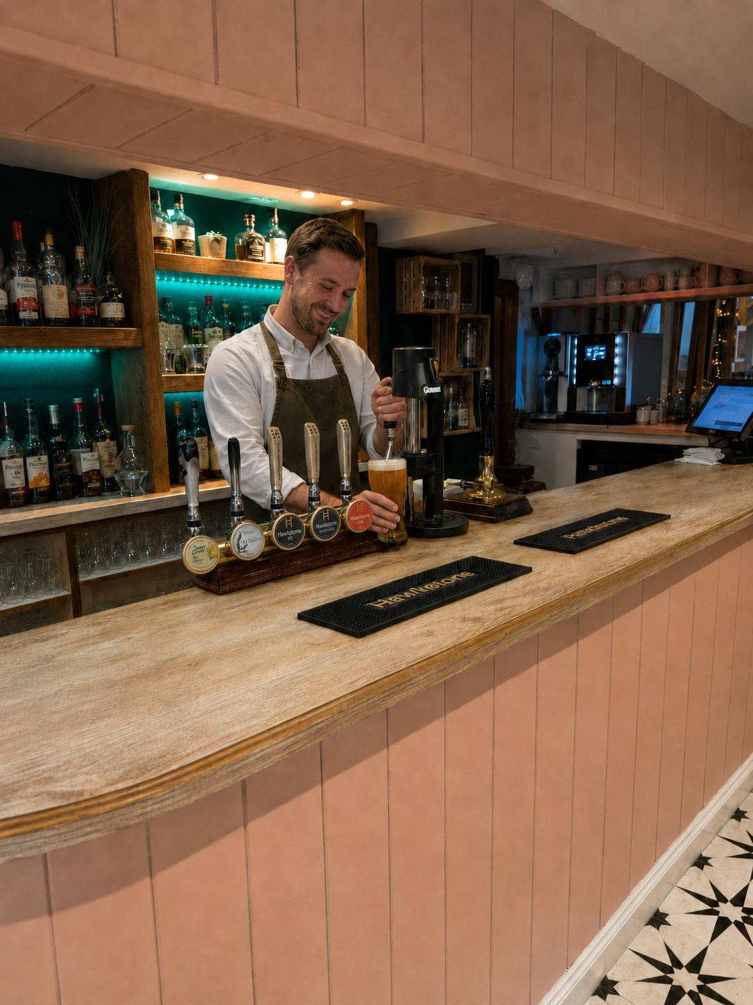 A friendly member of the Pig and Peacock team serving a pint at the illuminated bar