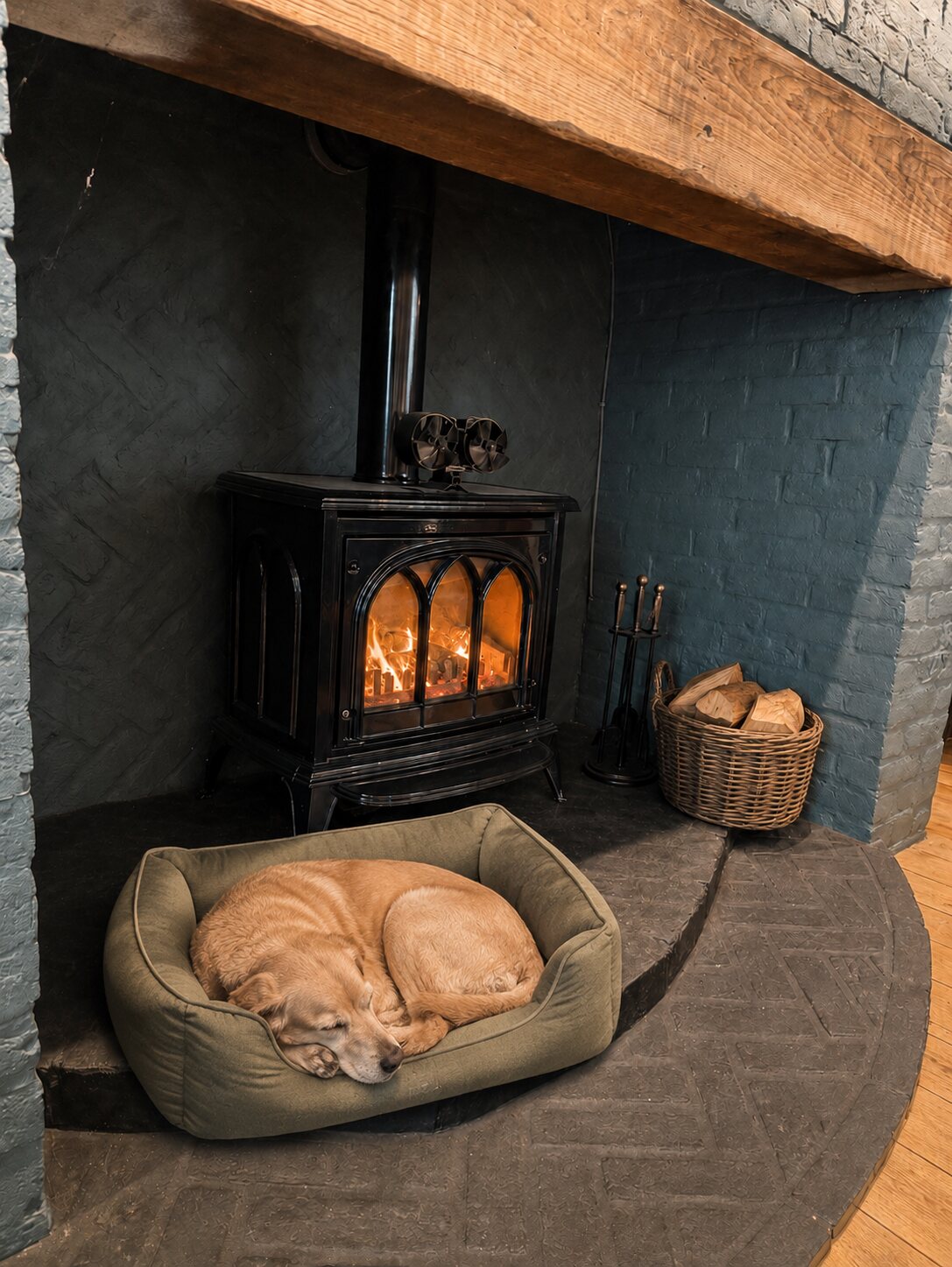 A dog sleeping in its bed beside the glowing pub stove