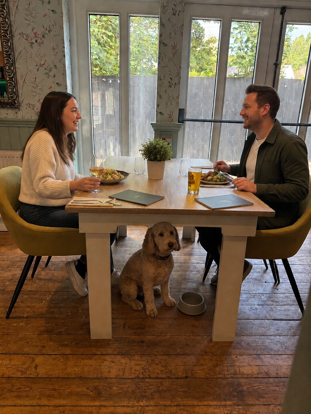 Two diners with menus, drinks and a dog resting beneath their table
