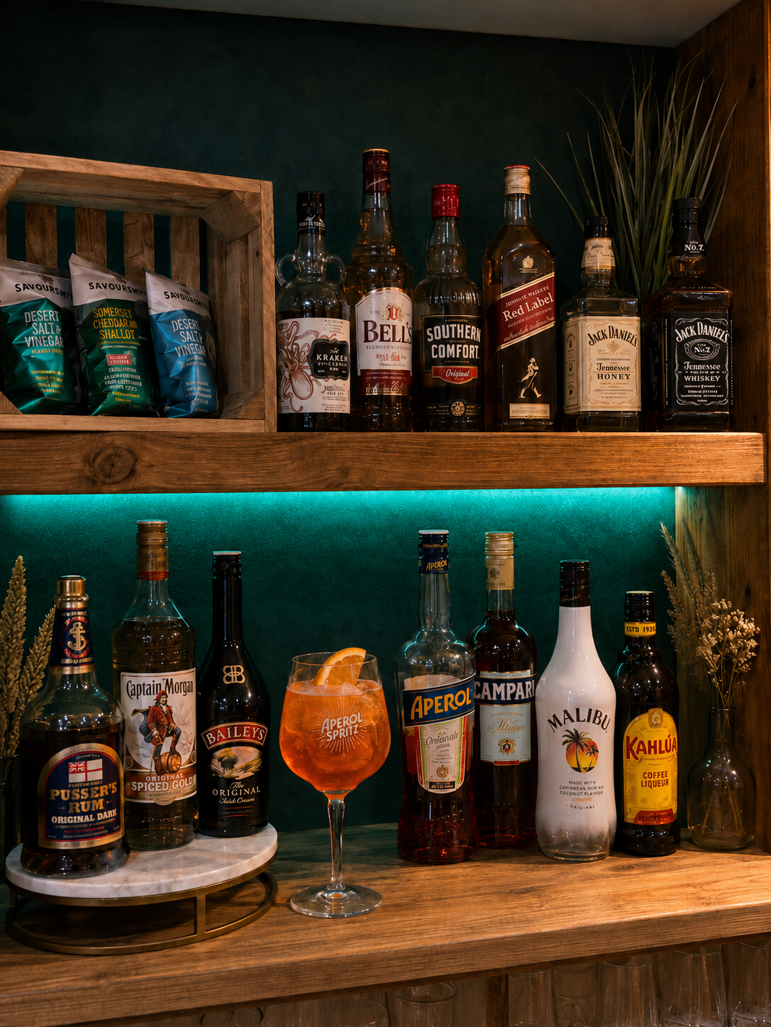 An Aperol Spritz and spirit selection at the green illuminated bar